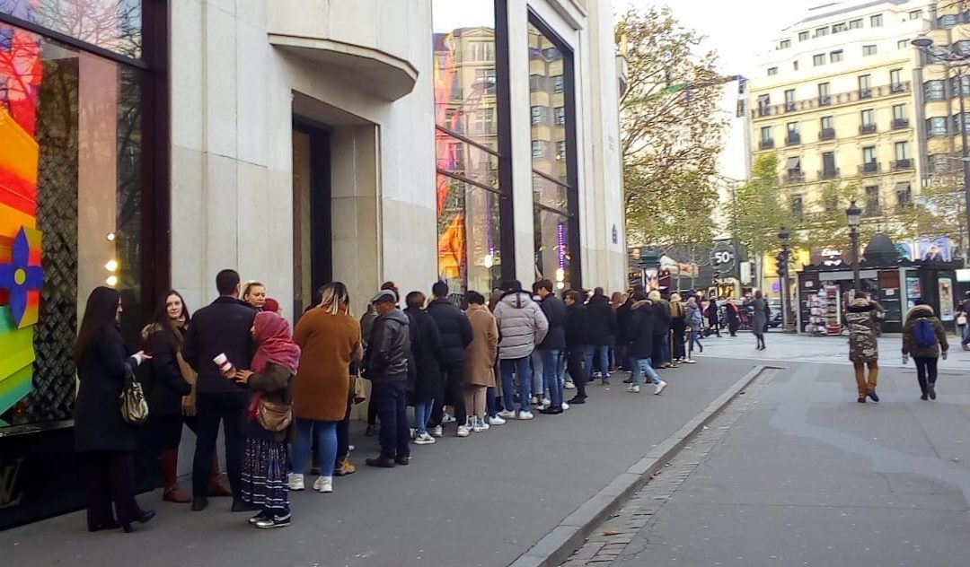 Uma mulher fora do cenário, numa fila em Paris
