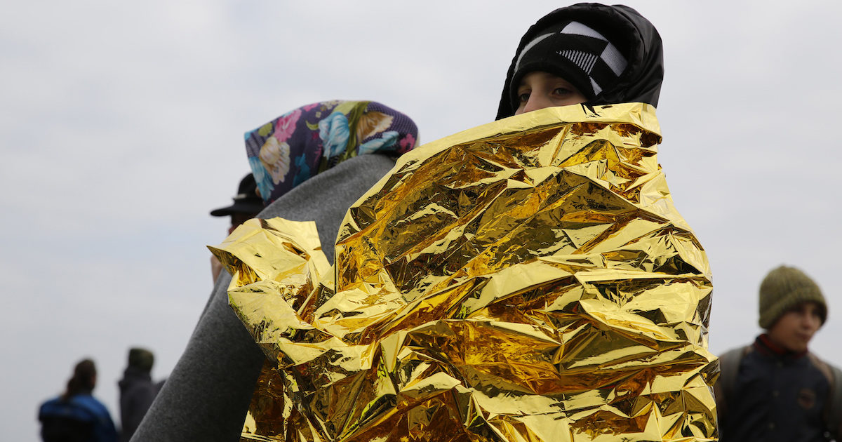 A migrant boy wrapped in a thermal blanket stands on the beach moments after the arrival of a rubber dinghy packed with refugees and migrants on the Greek island of Lesbos
