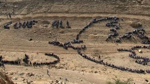 Vista aérea de um grupo de pessoas a replicar o desenho da pomba da paz de Picasso, numa criação do artista Jonh Quigley, no Monte das Tentações. Foto © UNRWA.