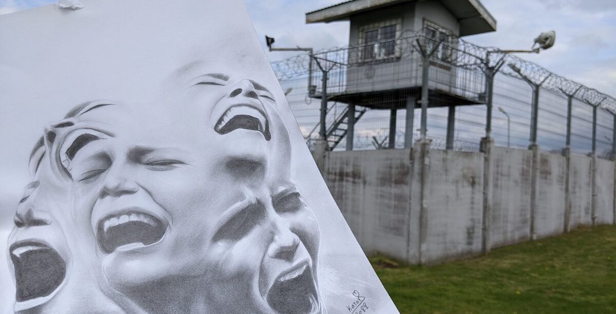 Fotografia-1-Lituania-scaled Karrar Español é um requerente de asilo iraquiano de 25 anos, atualmente detido na Lituânia no campo de Kybartai, que se vê por trás do seu trabalho artístico nesta imagem. Karrar é um artista dotado e partilhou o seu trabalho artístico Scream the Mind com a Amnistia Internacional para mostrar através dos seus olhos e mente como se sente ao ser detido apenas por querer pedir asilo. Karrar refere: "é muito difícil quando o artista vê os seus quadros terem mais liberdade do que ele. Isto é muito difícil. Neste momento, os meus quadros estão em cada país, em cada cidade, e dentro de cada casa, mas eu ainda estou na prisão". © Karrar Español.