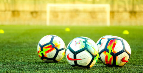 Amnistia Internacional quer jogo limpo nos direitos humanos para os Mundiais de futebol Bolas de futebol num campo. Foto © Travel Nomades | Unsplash