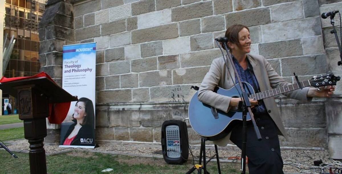 Maeve Louise Heaney a tocar, no exterior da Catedral de St. Stephen, em Brisbane, na Austrália. Foto retirada do Facebook da autora.