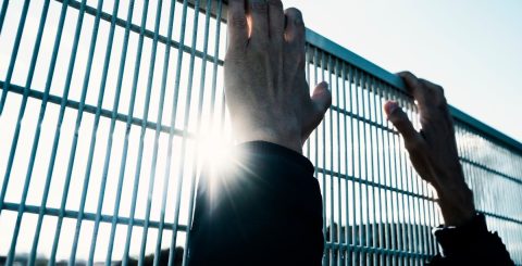 Governo britânico impedido de deportar requerentes de asilo para o Ruanda Homem tentando subir cerca. Foto © Juan Moyano