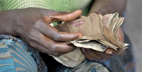 Uma mulher conta o seu dinheiro num mercado em Kamina, na República Democrática do Congo. Construído pelo Comité Metodista Unido de Ajuda (UMCOR). Foto Paul JeffreyVida na Terra