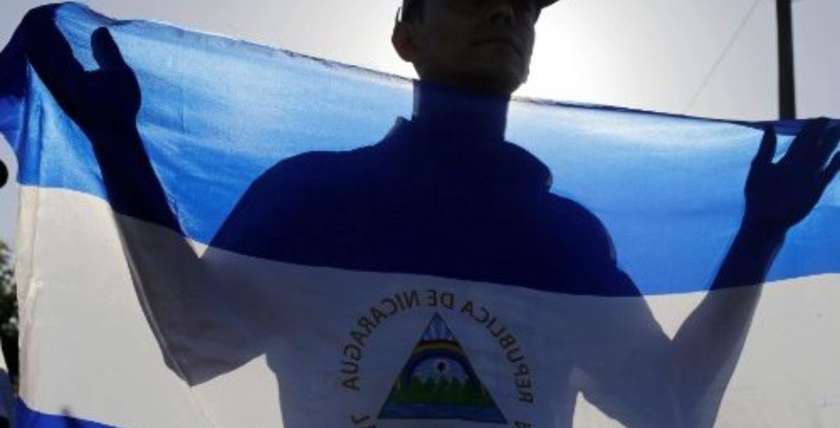 Um homem segura uma bandeira nacional durante uma missa pela paz na Nicarágua na catedral de Manágua. Foto Vatican Media