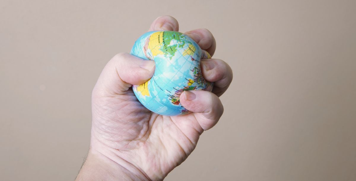 Uma mão estrangula o planeta terra. Foto Axel Bueckert