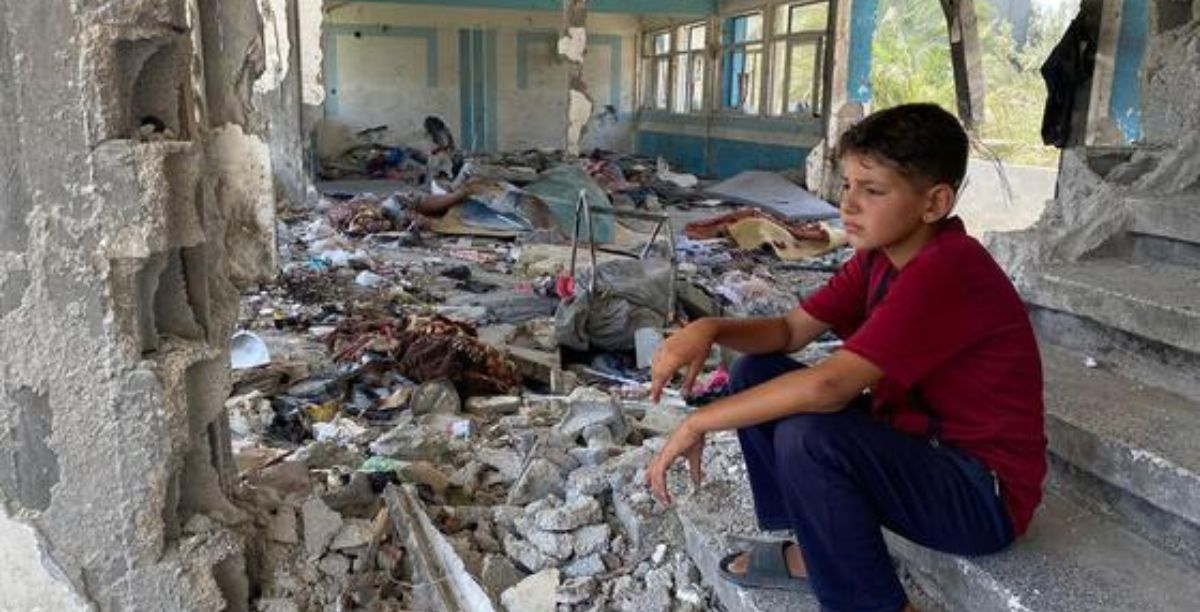 © UnrwaFadi Thabet Criança sentada entre as ruínas de uma escola no centro de Gaza