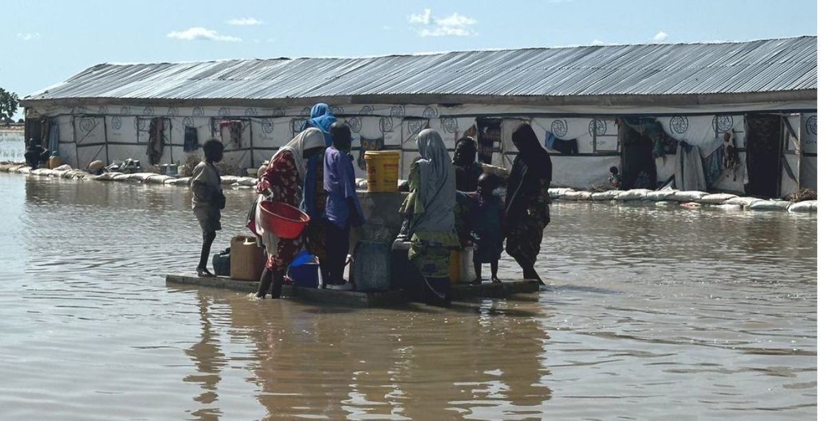 © ACNUR Famílias atravessam as águas da enchente para acessar um ponto de água em um local para deslocados internos em Dikwa, no estado de Borno, no nordeste da Nigéria.