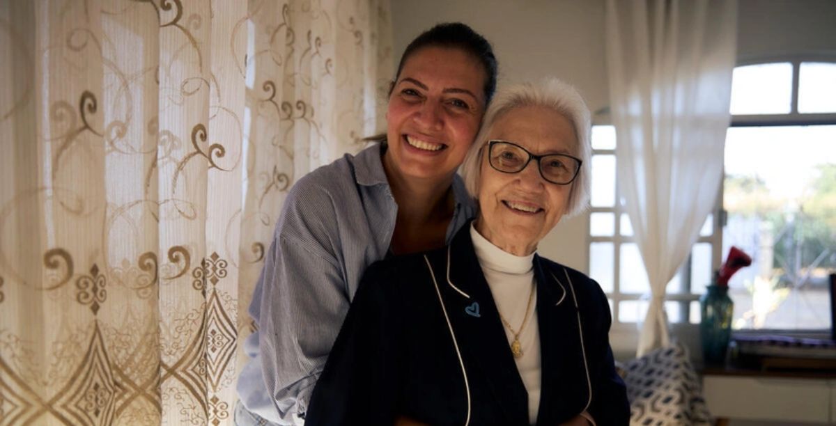Jana Alraee abraça sua amiga Irmã Rosita dentro de sua casa em um bairro residencial de Brasília. © ACNURMarina Calderon