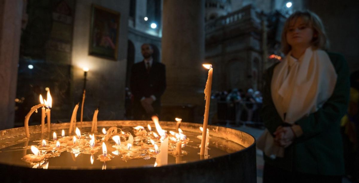 Uma mulher faz uma pausa em um conjunto de velas de oração dentro da Igreja do Santo Sepulcro, Jerusalém, Terra Santa: Essas velas são deformadas e imperfeitas, mas ainda transmitem luz e esperança. Foto: Albin Hillert/CMI