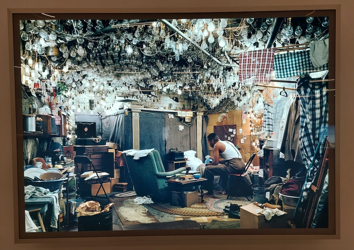 Homem num quarto saturado de lâmpadas, apenas algumas acesas, na exposição Jeff Wall. Time Stands Still. Fotografias, 1980-2023, no MAAT em Lisboa. Foto © José Alves Jana.