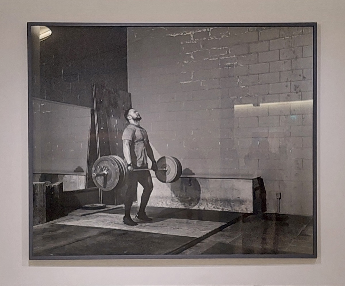 Um homem pratica halterofilismo, , na exposição Jeff Wall. Time Stands Still. Fotografias, 1980-2023, no MAAT em Lisboa. Foto © José Alves Jana.