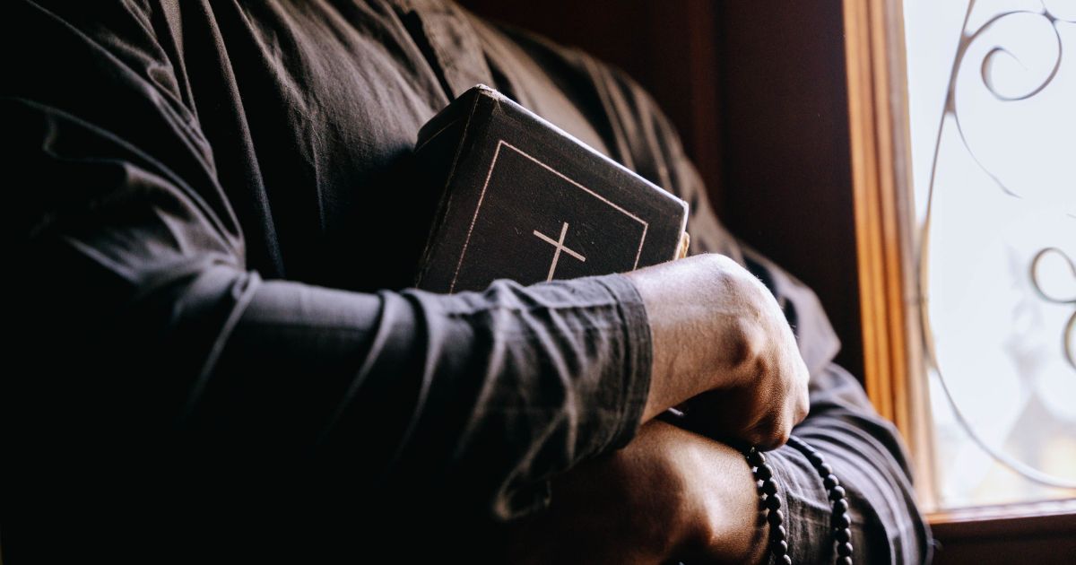 Padre a segurar Bíblia. Foto Ivan S Pexels Padre a segurar Bíblia. Foto Ivan S Pexels