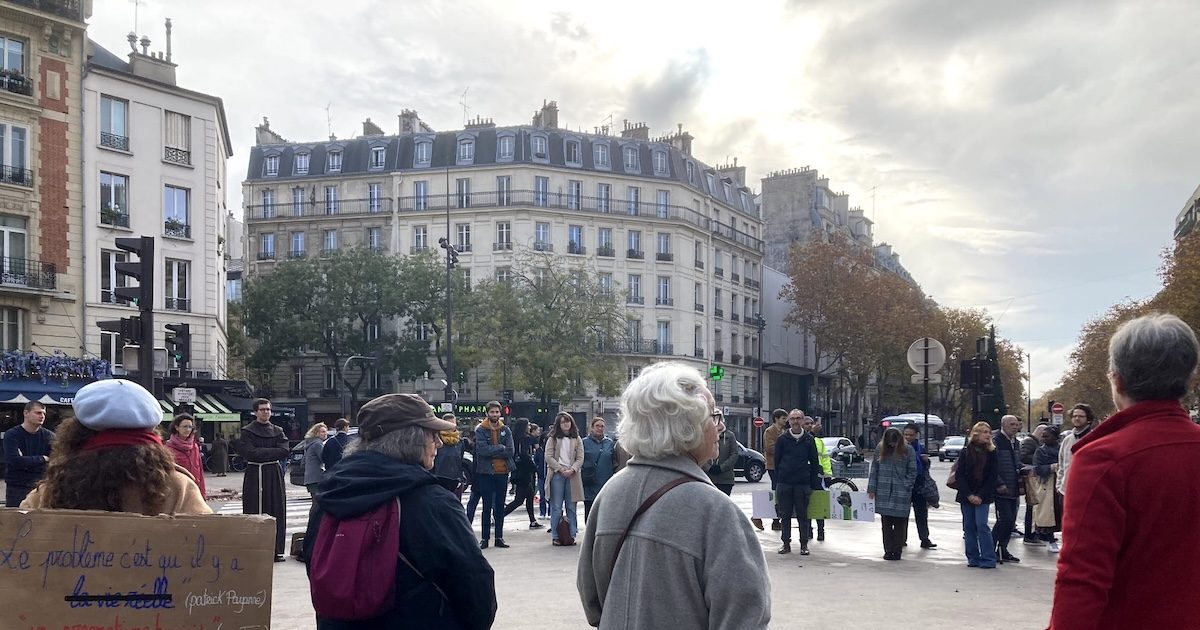 Pessoas fazem um círculo de silêncio num lugar público, empunhando cartazes a pedir uma conversão ecológica, aqui em Paris (França), este domingo, 16 de novembro. Foto: Direitos reservados.