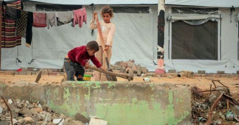 © UnicefMohammed Nateel Duas crianças limpam os destroços do lado de fora de uma tenda na cidade de Gaza