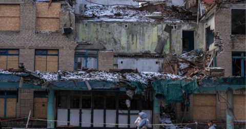 © UNICEFOleksii Filippov Civis passam por um edifício danificado pela guerra na Ucrânia.