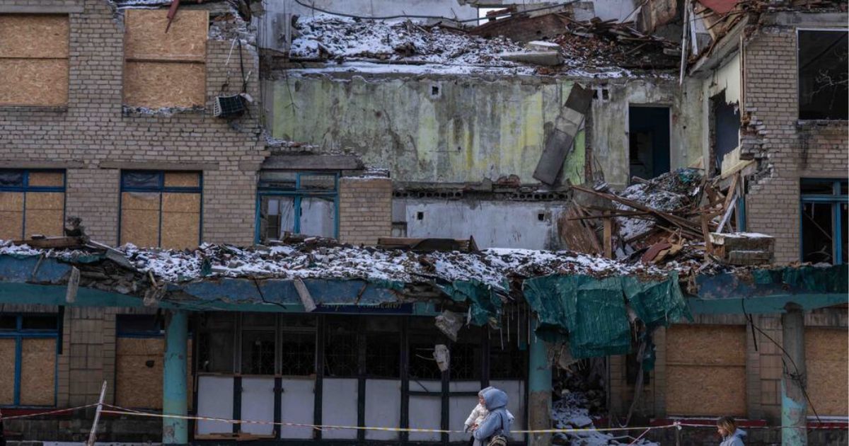 © UNICEFOleksii Filippov Civis passam por um edifício danificado pela guerra na Ucrânia.