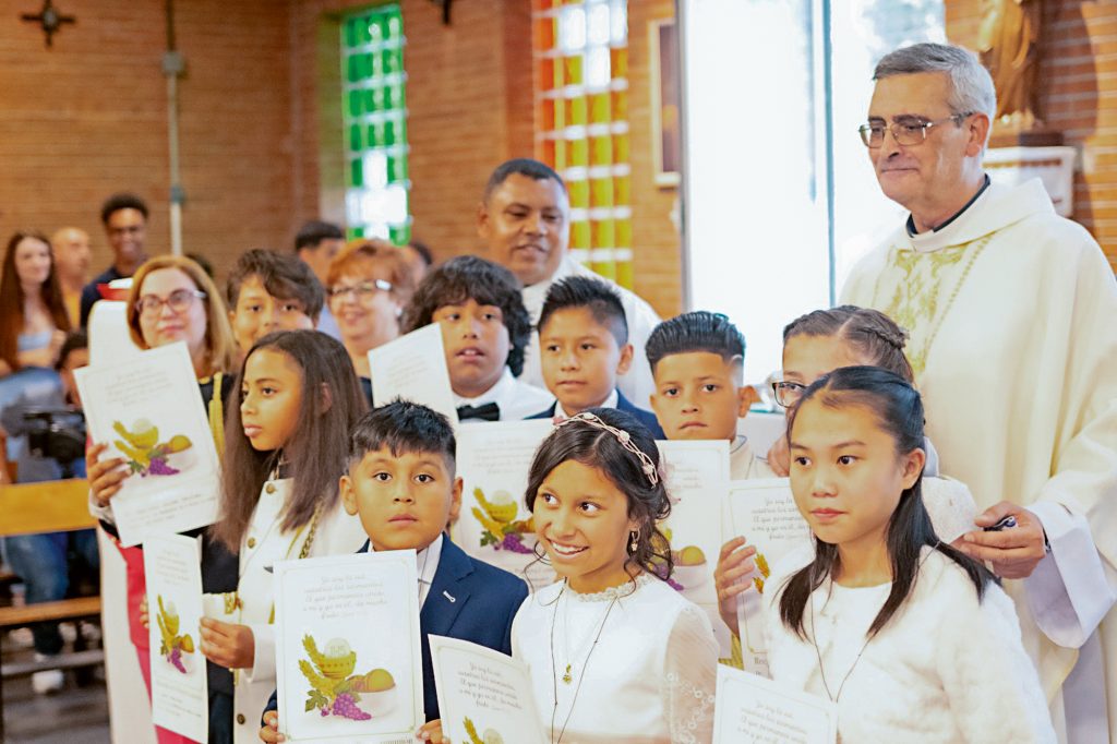 Padre português junto de crianças que realizaram a Primeira Comunhão em maio de 2024