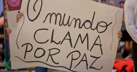 O mundo clama por paz (O mundo clama por paz) diz a placa segurada por um jovem participante da 11ª Assembleia do Conselho Mundial de Igrejas, realizada em Karlsruhe, Alemanha, em 2022. Foto Paul